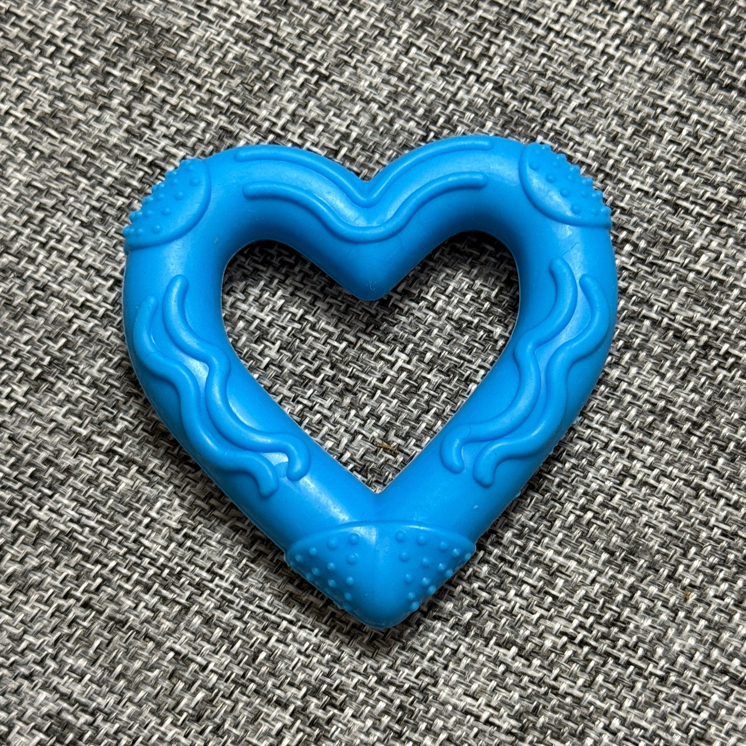 Blue heart-shaped rubber dog chew toy on textured gray fabric background