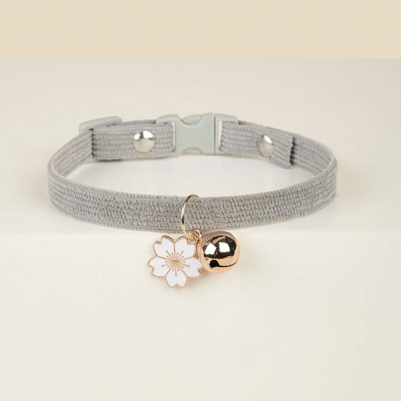 Gray pet collar with cherry blossom charm and gold bell on white background