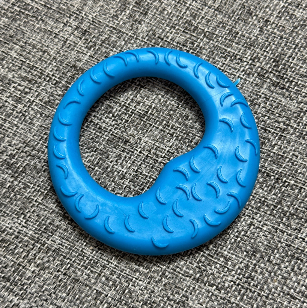 Blue textured rubber dog chew toy ring on a gray fabric background