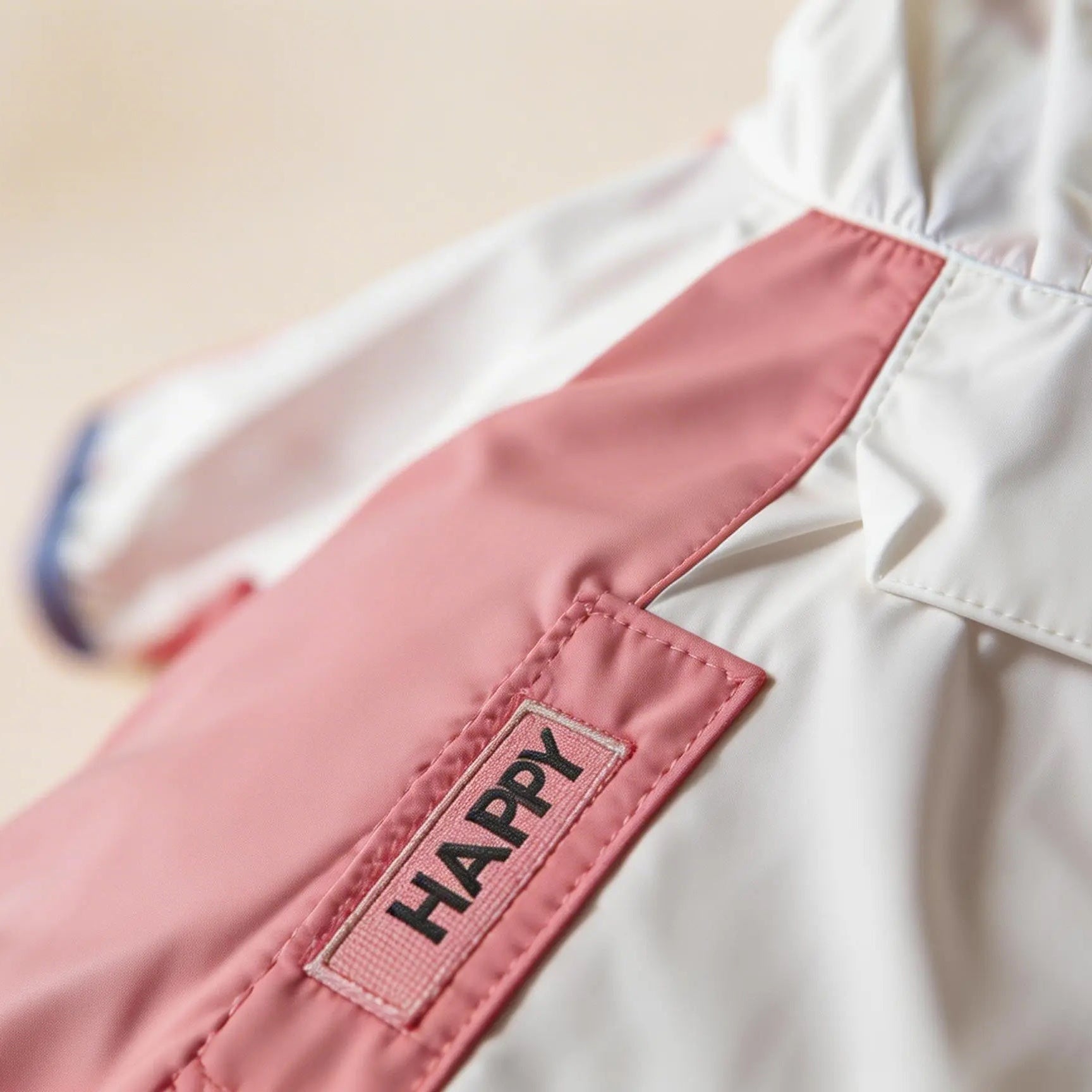 Pink and white pet jacket with 'HAPPY' patch, stylish dog clothing close-up.