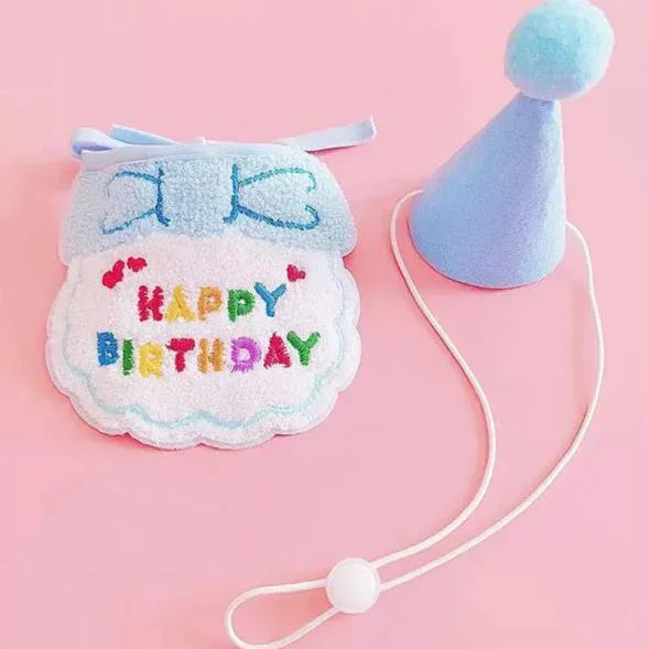 Pet birthday outfit set with blue party hat and 'Happy Birthday' embroidered bib on pink background