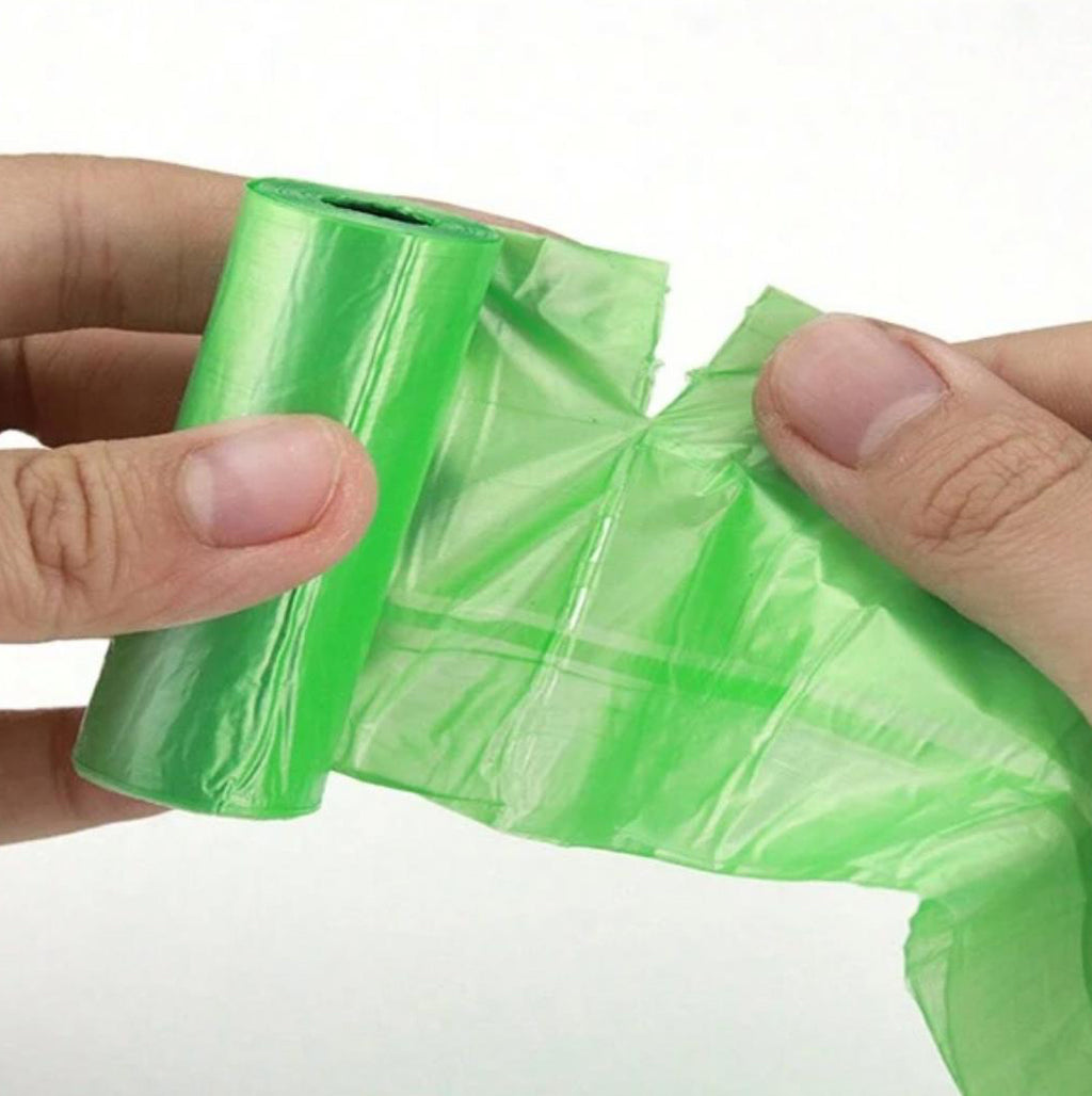 Hands separating a green roll of pet waste bags, dog poop bags for cleanup