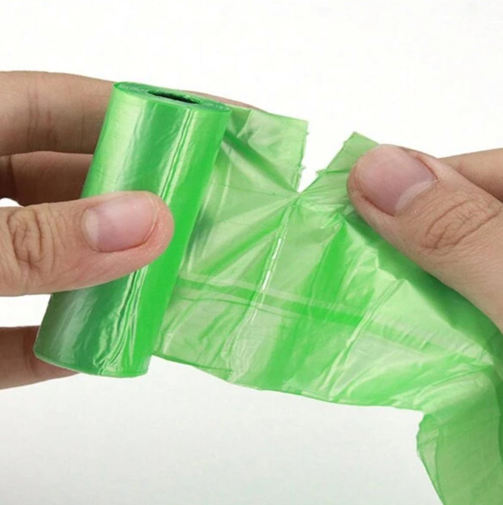Hands separating a green roll of pet waste bags, dog poop bags for cleanup
