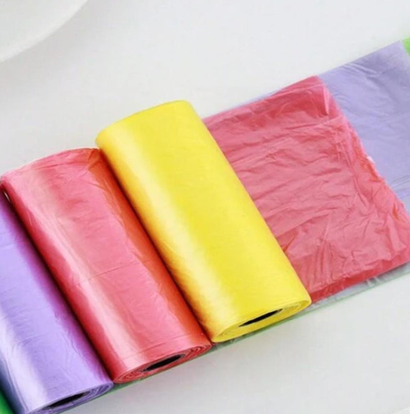 Colorful rolls of pet waste bags in purple, red, yellow, and pink on a white surface