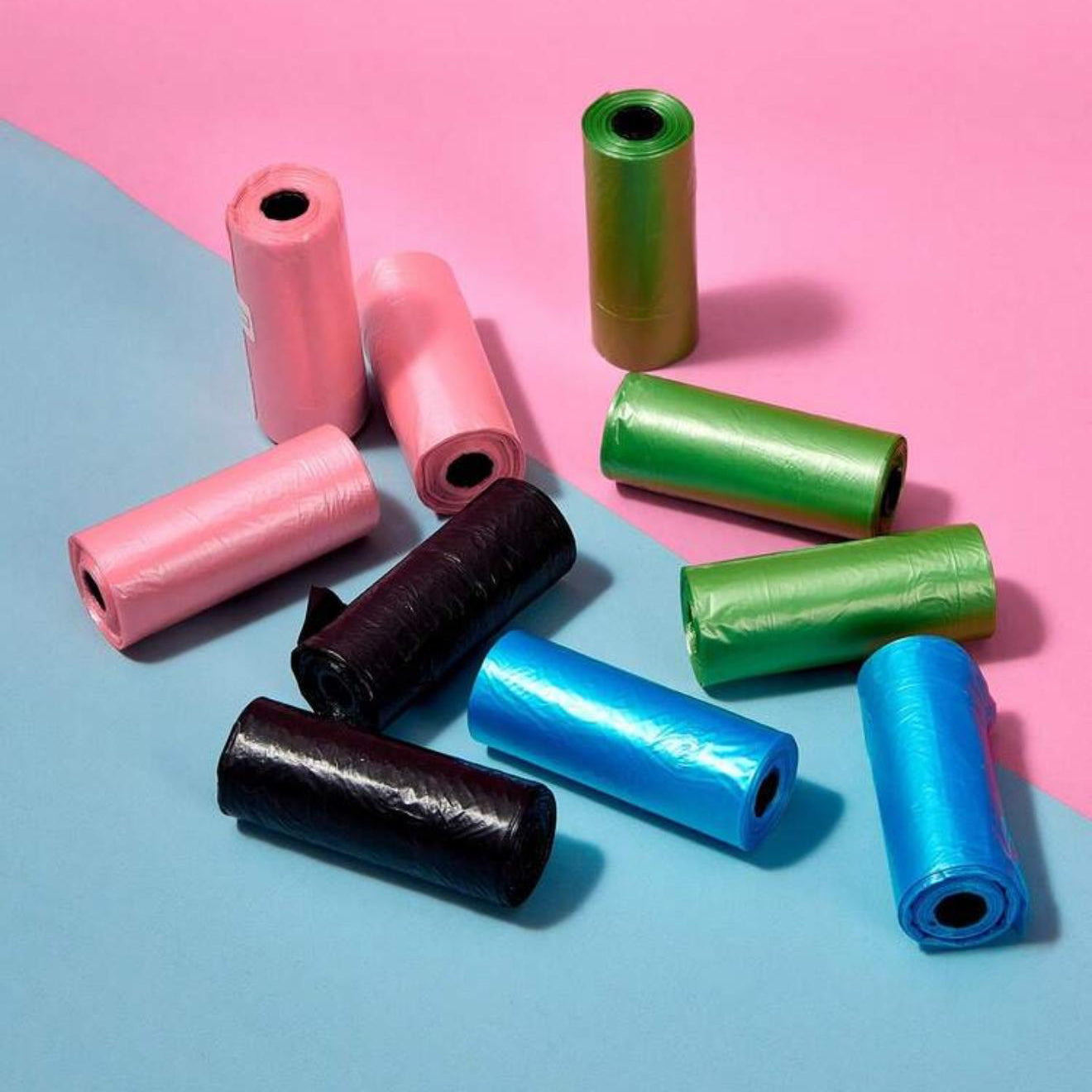 Colorful pet waste bag rolls on pink and blue background, essential pet accessory