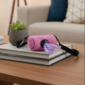 Pink dog waste bag dispenser with strap on coffee table, living room background