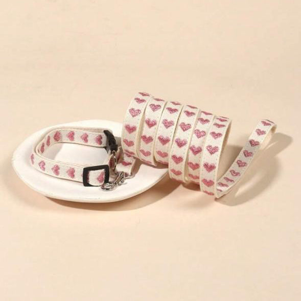White pet collar and leash set with pink heart pattern on beige background