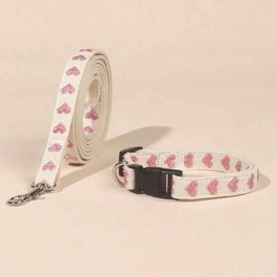 White pet collar and leash set with pink heart pattern on neutral background