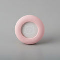 Pink round pet accessory with a cat face design on gray background