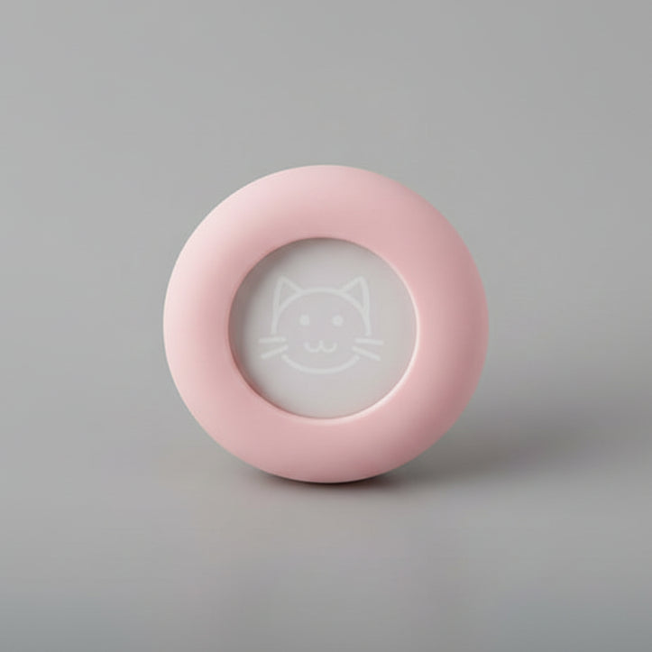 Pink round pet accessory with a cat face design on gray background