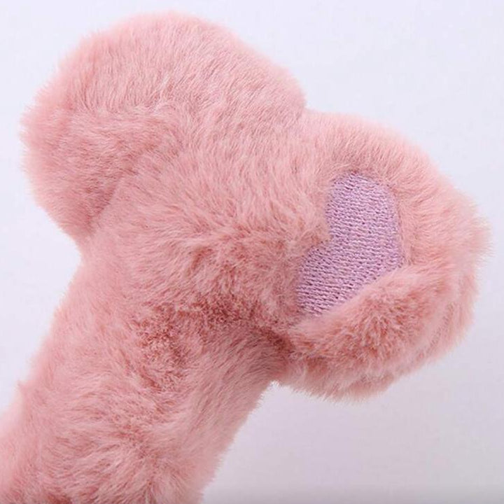 Pink plush dog bone toy with soft fur texture and fabric patch, pet accessory