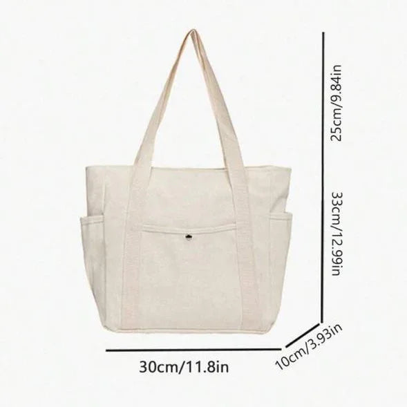 Beige canvas tote bag with side pockets and size measurements in cm and inches.
