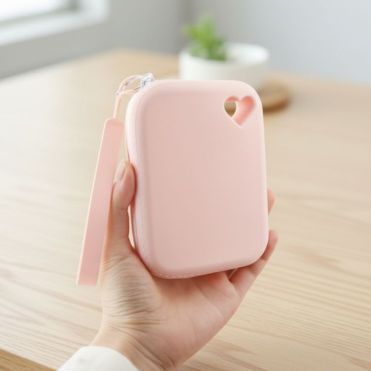 Hand holding a small pink zipper pouch with heart-shaped cutout, pet accessory pouch