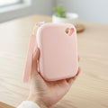 Hand holding a small pink zipper pouch with heart-shaped cutout, pet accessory pouch