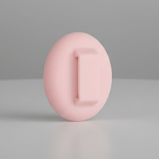 Pink oval silicone pet grooming brush on a neutral background