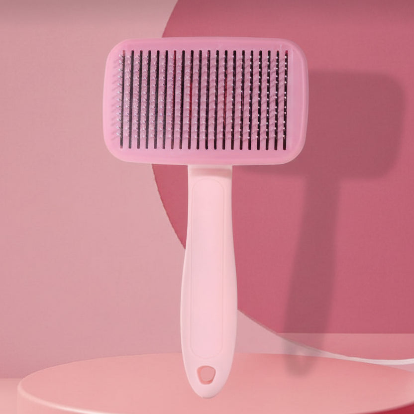Pink pet grooming brush with fine bristles for cats and dogs on a pink background.